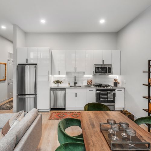 Contemporary kitchen with white cabinets, green chairs, wood table, and open shelving