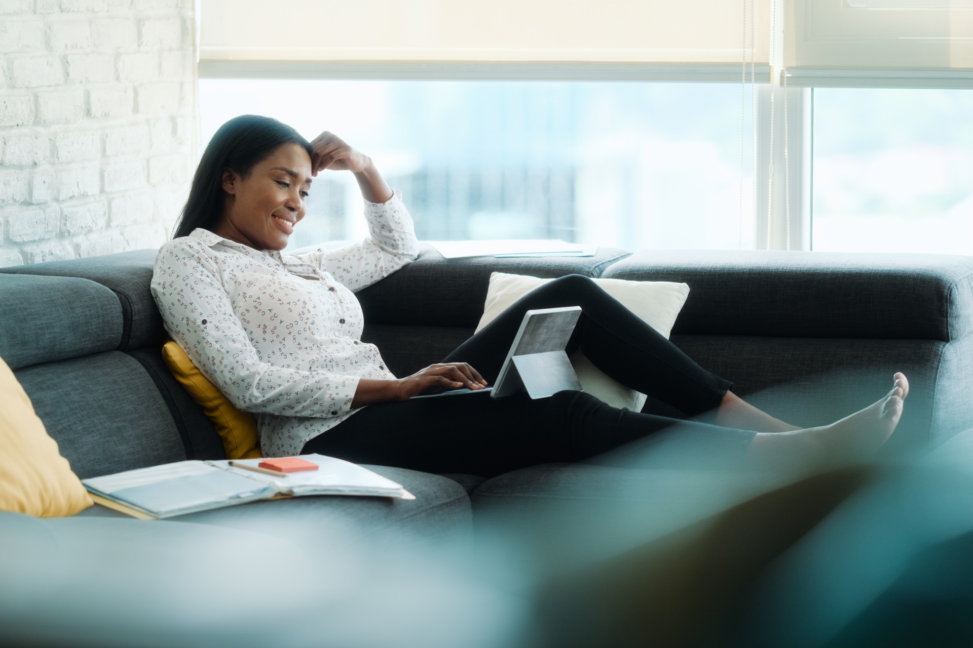 A woman seated on a couch & focused on her laptop