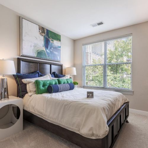 Photo of bedroom showing a bed filled with throw pillows and a dresser and nightstand