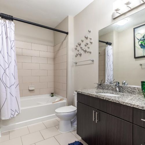 Photo of bathroom with white tub, tiled floors, and marble counters surrounding the sink
