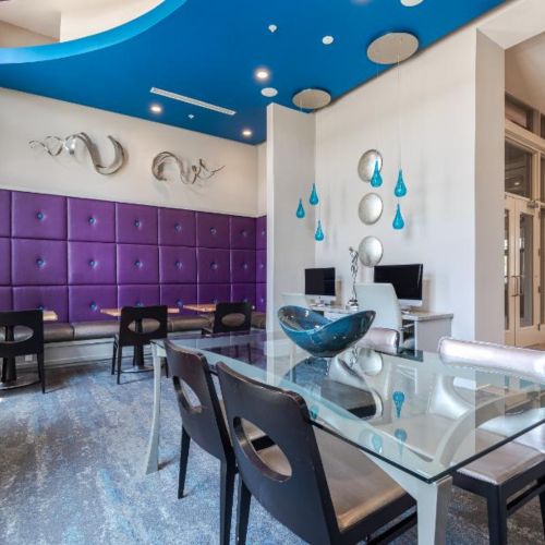 Photo of eCafe with two computers, multipe desks with chairs, and a glass table surrounded by 4 chairs