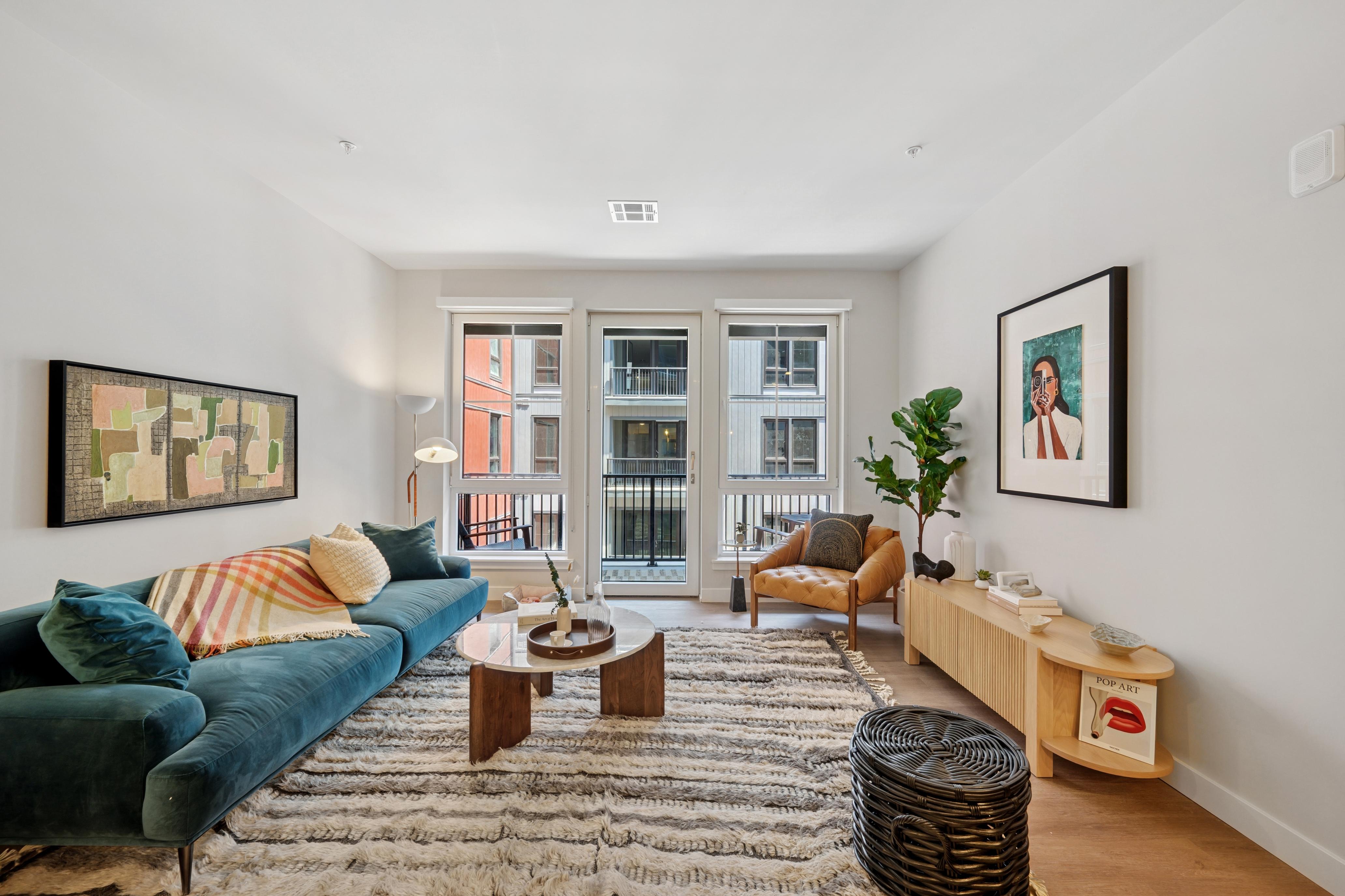 Modern living room with emerald sofa, open kitchen, island seating, and woven wall art