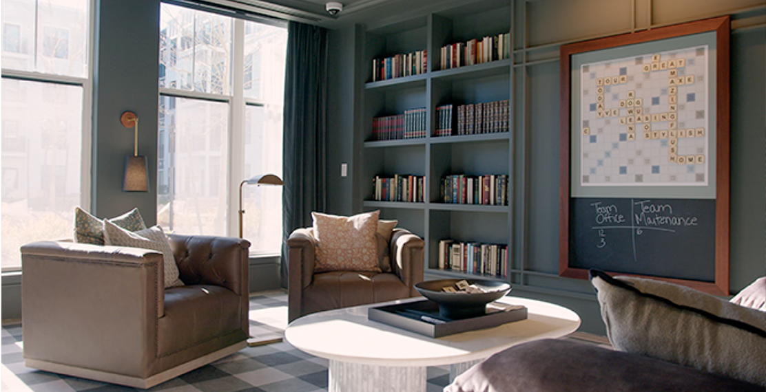 Cozy apartment lounge with chairs and bookshelves.