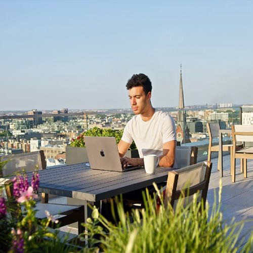 Resident working on a laptop at a rooftop table.